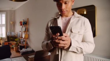 Genç gülümseyen Asyalı adamın evinde cep telefonuyla yüksek kaliteli 4K görüntüler yolluyor.