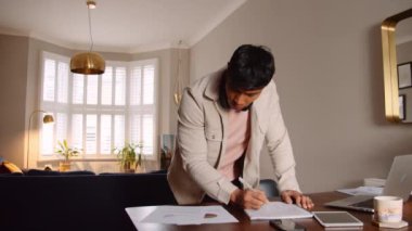 Asyalı bir adam ofisinde masasının başında durup not alıyor. Yüksek kalite 4k görüntü