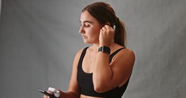 Caucasian Young Woman Focused Putting Her Ear Pods While Her — Stock Video