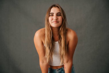 Beyaz kadın, uzun sarı saçları, omuzları öne doğru sırıtarak gülümsüyor. Yüksek kalite fotoğraf