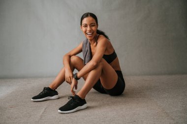 African American female sitting on the floor in her sportwear and sneakers smiling and feeling great after work out . High quality photo