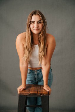 Kotunun içinde elleri tabureye yaslanmış uzun sarı saçları olan genç bayanı kapatın. Yüksek kalite fotoğraf