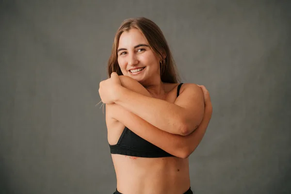 Close up Caucasian female with big smile hugging herself in the studio. High quality photo