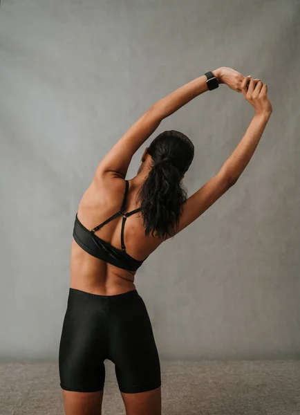 African American female doing a waist stretching exercise with her fit bit watch in her ports wear. High quality photo