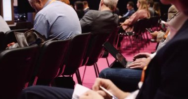  Close up of people seated in an auditorium listening to lecture and taking notes and using there laptops. High quality 4k footage