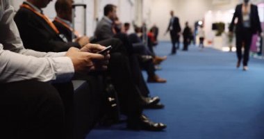  Convention center men in suits on there cellphones siting on chairs working . High quality 4k footage