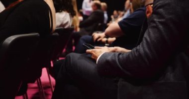 People seated in an auditorium listening to lecture typing on there cellphone . High quality 4k footage