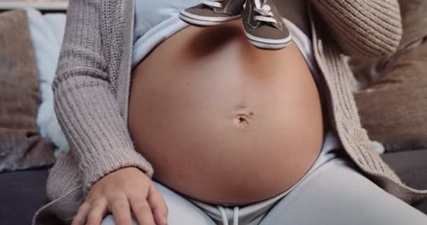 Portrait Pregnant Female Putting Baby Shoes Her Baby Bump Sitting — Stockvideo