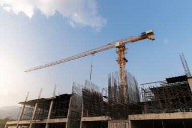 Gökyüzü ve güneşin arka planında vinçleri olan inşaat alanı.