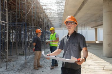 Mimar, Mühendis, Müteahhit ya da İnşaat Yöneticisi bir inşaat sahasında bir grupla birlikte projeyi tutuyor..