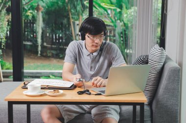 İş adamı video görüşmesi. Müşteriler ofisteki laptopta. Adam kulaklık takıyor ya da internetten eğitim alıyor..