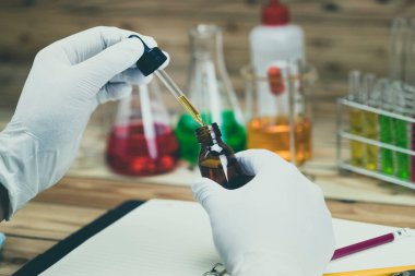 Araştırmacı, test tüpüne reaktörü bırakıyor. Laboratuvarda çalışan bir bilim adamı..