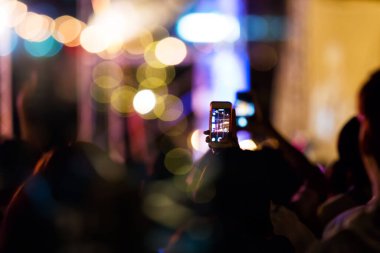 Audience take a photo on mobile phone at a free night concert music festival.