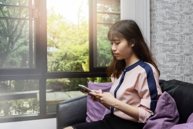 Antika bir kafede otururken cep telefonu kullanan güzel bir Asyalı kadın.