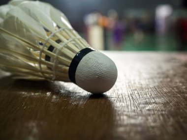 Beyaz badminton servis aletinin parke zeminde yakın plan çekimi..