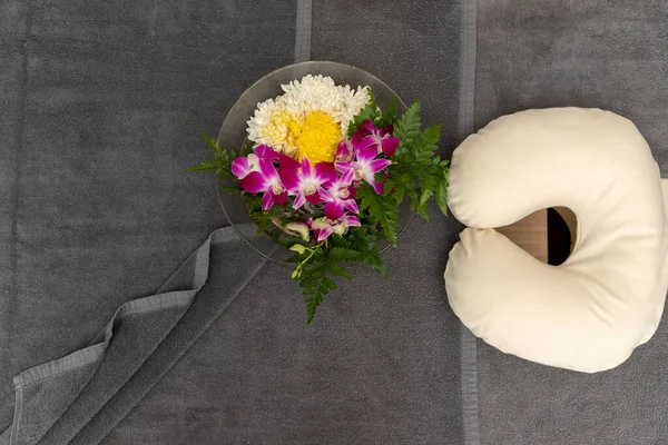 Pillow with Towel and flower on massage table in modern spa salon