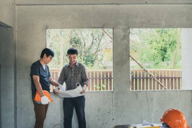 Mühendis ve mimar inşaat alanındaki projeyi ustabaşıyla tartışıyor.