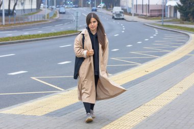 Uzun paltolu güzel bir kız ıssız bir caddede yürüyor.