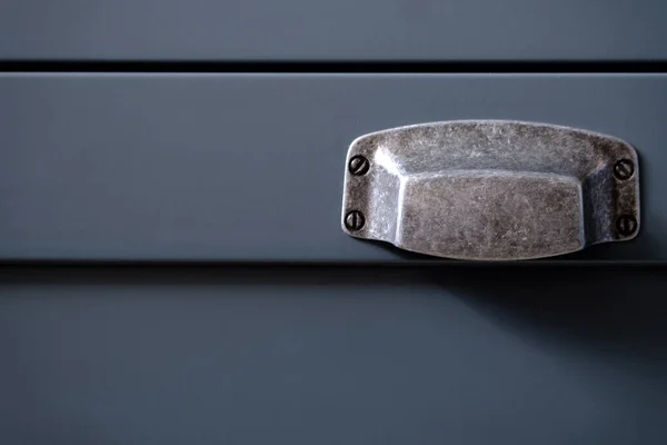 Stylish metal matte furniture handle on facade of gray kitchen cabinet, selective focus