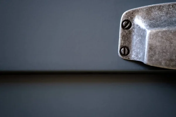 Stylish metal matte furniture handle on facade of gray kitchen cabinet, selective focus