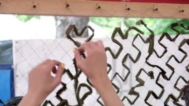 Kadınların elleri ordu için kamuflaj ağı örüyor, gönüllü olarak askeri ihtiyaçlar için kamuflaj koruması yapıyor, seçici bir şekilde odaklanıyor.