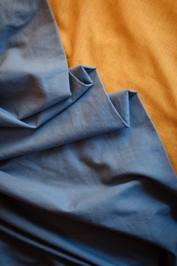 Bicolor background gray and orange fabric, crumpled fabric folds, selective focus