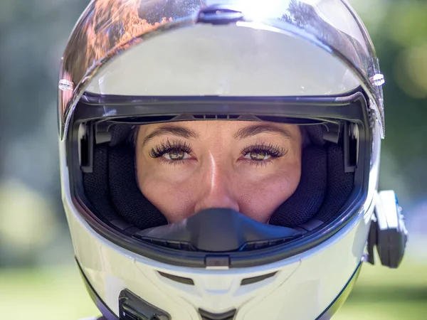 Close up head shot of a pretty young female wearing a bluetooth motorcycle helmet