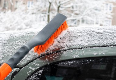 Arabayı bir fırçayla kardan temizlemek. Seçici odaklanma. Ulaşım, kış, hava durumu, insanlar ve araç kavramı 