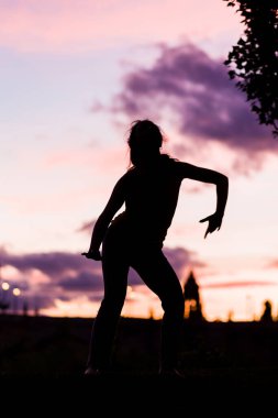 Alacakaranlıkta ya da günbatımında bir balerin silueti müzikle pozitif hareket eder. 