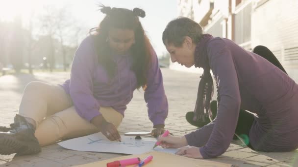 Две мультикультурные женщины готовят плакаты для протеста феминизма 8 марта. Кубинская и испаноязычная замедленная съемка — стоковое видео