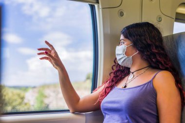 hispanic female travel with melancholy and nostalgic mood. lifestyle travelling portrait trip with covid-19 face mask prevention