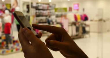 Giyim mağazası, alışveriş merkezi ve süpermarket karşı bir akıllı telefon kullanan 4 k A kadın.