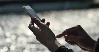 Deniz kenarında, köpüklü su yüzeyi bir akıllı telefon kullanan 4 k A kız.
