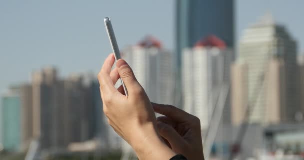 4k Una chica usando un teléfono inteligente contra el fondo moderno edificio de negocios . — Vídeo de stock