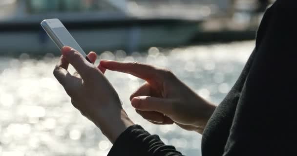 4k Seorang gadis menggunakan smartphone di tepi laut, kapal pesiar & berlayar di pelabuhan . — Stok Video