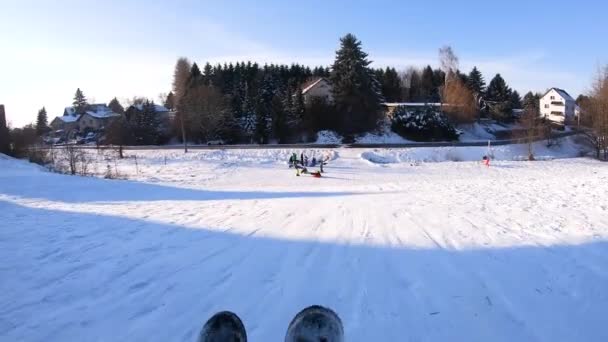 Дети катаются на санках по заснеженным холмам. Дети катаются на санках по снегу зимой — стоковое видео