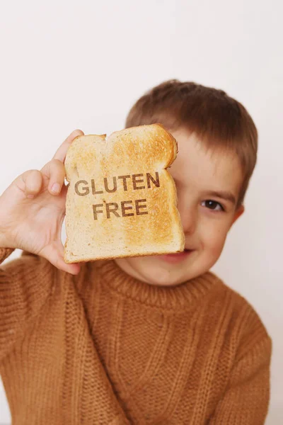 Preschool boy with toasted bread without gluten. Healthy food. Gluten intolerance by children.