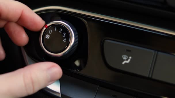 Hand draait airconditioner ring. De chauffeurs bedienen de airconditioner op een zwart glimmend dashboard. Close-up. — Stockvideo
