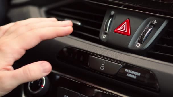 Hand turns air conditioner ring. The drivers hand controls air conditioner on a black shiny car dashboard. Close-up. — Stock Video