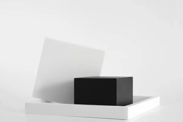 Μαύρο βάθρο με λευκά απλά γεωμετρικά σχήματα στο λευκό φόντο. Στόμιο για το προϊόν, καλλυντική παρουσίαση. Δημιουργική κοροϊδία. Pedestal ή πλατφόρμα για τα προϊόντα ομορφιάς. — Φωτογραφία Αρχείου