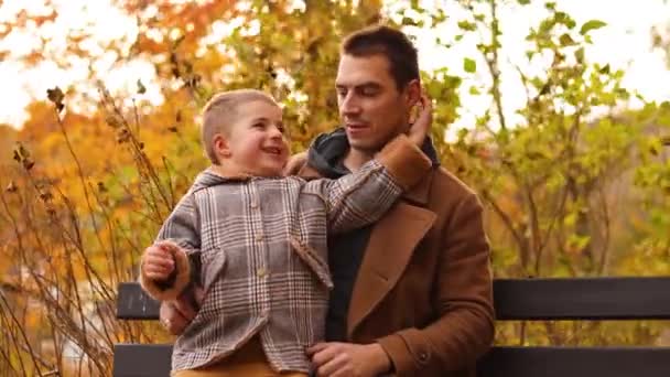 Hezký bělošský otec se baví se svými roztomilými dětmi. Podzimní park s spadlým podzimním listím. Muž a dvě děti, chlapci. Otec mluví se synem. Rodinná láska. — Stock video