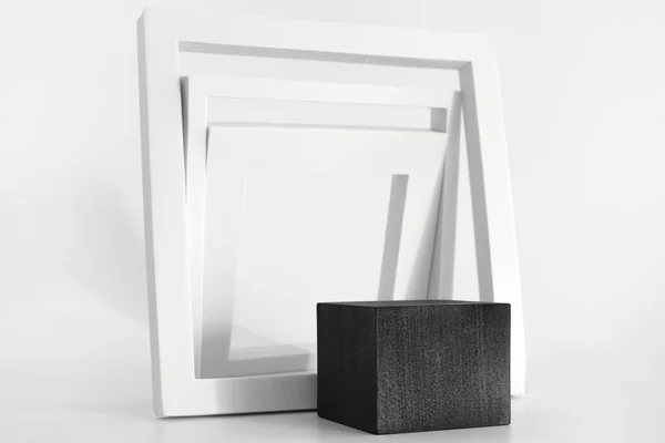 Μαύρο βάθρο με λευκά απλά γεωμετρικά σχήματα στο λευκό φόντο. Στόμιο για το προϊόν, καλλυντική παρουσίαση. Δημιουργική κοροϊδία. Pedestal ή πλατφόρμα για τα προϊόντα ομορφιάς. — Φωτογραφία Αρχείου
