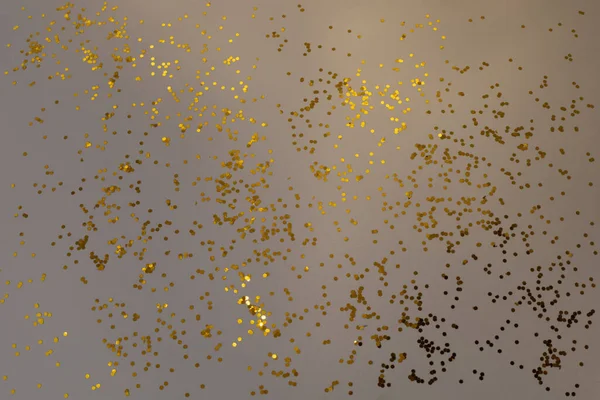 Goldenes Glitzerkonfetti auf grauem Hintergrund. Glänzende Partikel, dekorativer abstrakter Hintergrund. Party, Frohe Weihnachten, Frohes Neues Jahr. — Stockfoto