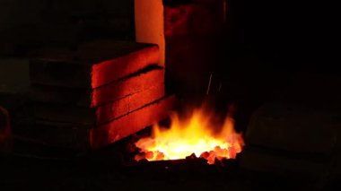 Demircide çalışan demirci, ateşte ısıtan metal. Demirciden metal eşyalar yapmak. Ateş alevindeki kırmızı, sıcak demir parçası işlemler için hazır..