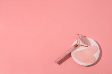 Pembe arka planda Gua Sha masaj aletleri. Kuvars silindiri, yüz masajı ve rahatlama. Evde yaş sınırlaması ve kaldırma. Metin için boş alan, kopyalama alanı. Güzellik arka planı.