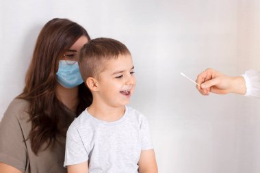 Covid 19 çocuk testi. Doktor ya da hemşire, geniz ya da ağız temizleme yöntemi kullanarak küçük çocuğa koronavirüs testi yapıyor. Risk ve enfeksiyon kontrol konsepti. Çocukların sağlığı. Mutlu, gülümseyen çocuk.