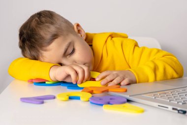 Küçük çocuk evde dizüstü bilgisayarla alfabe ve rakamları internetten öğreniyor. Çocuk üzgün ve yorgun. Olumsuz duygular, stres, zihinsel sorunlar. Çocuklar için ev eğitimi ve uzaktan eğitim.