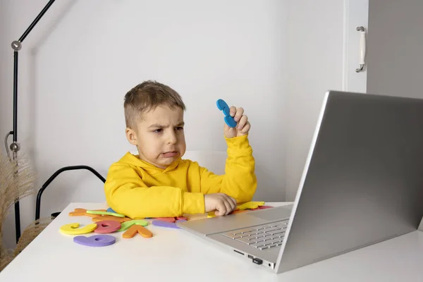 Little boy learning alphabet and numbers online, with laptop at home. Child is sad and tired. Negative emotions, stress, mental problems. Homeschooling and distance education for kids. — Stock Photo, Image