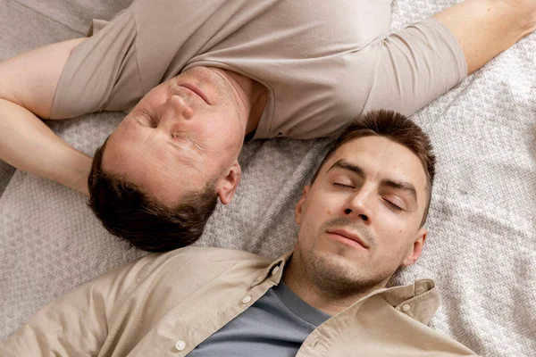 Šťastný gay pár s neformálním oblečením tráví čas doma. Dva běloši odpočívají. Homosexuální vztahy a alternativní láska. Útulný interiér. — Stock fotografie