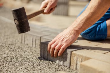 Gri beton döşeme döşeme döşeme döşeme döşeme döşeme genç adam ev avlusunda temel çakıl. Usta kaldırım taşlarını serer. Profesyonel kaldırım işçisi tarafından kaldırım taşı döşenmiş. Kaldırımları onarıyorum..